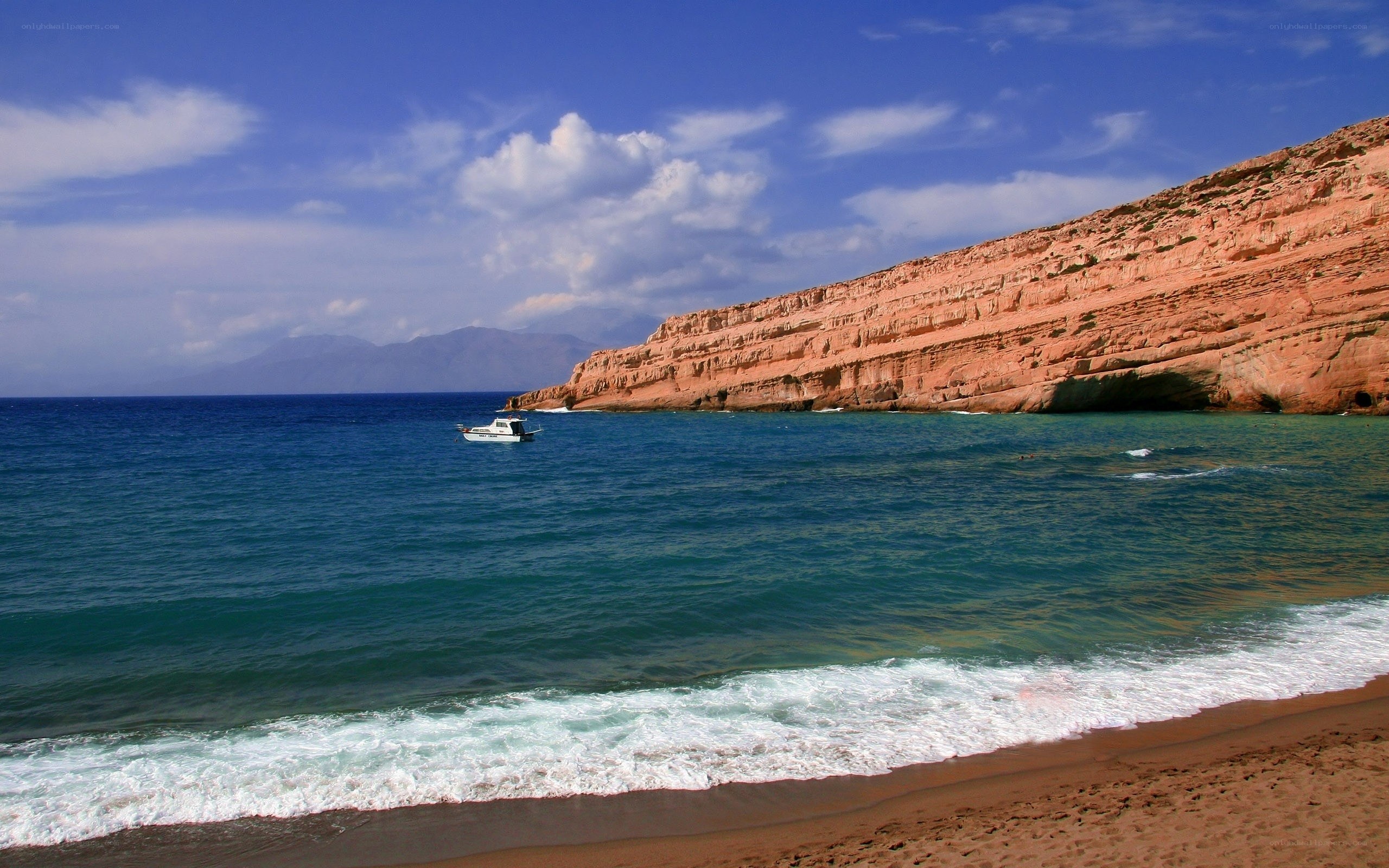 Beach with red cliffs and boat