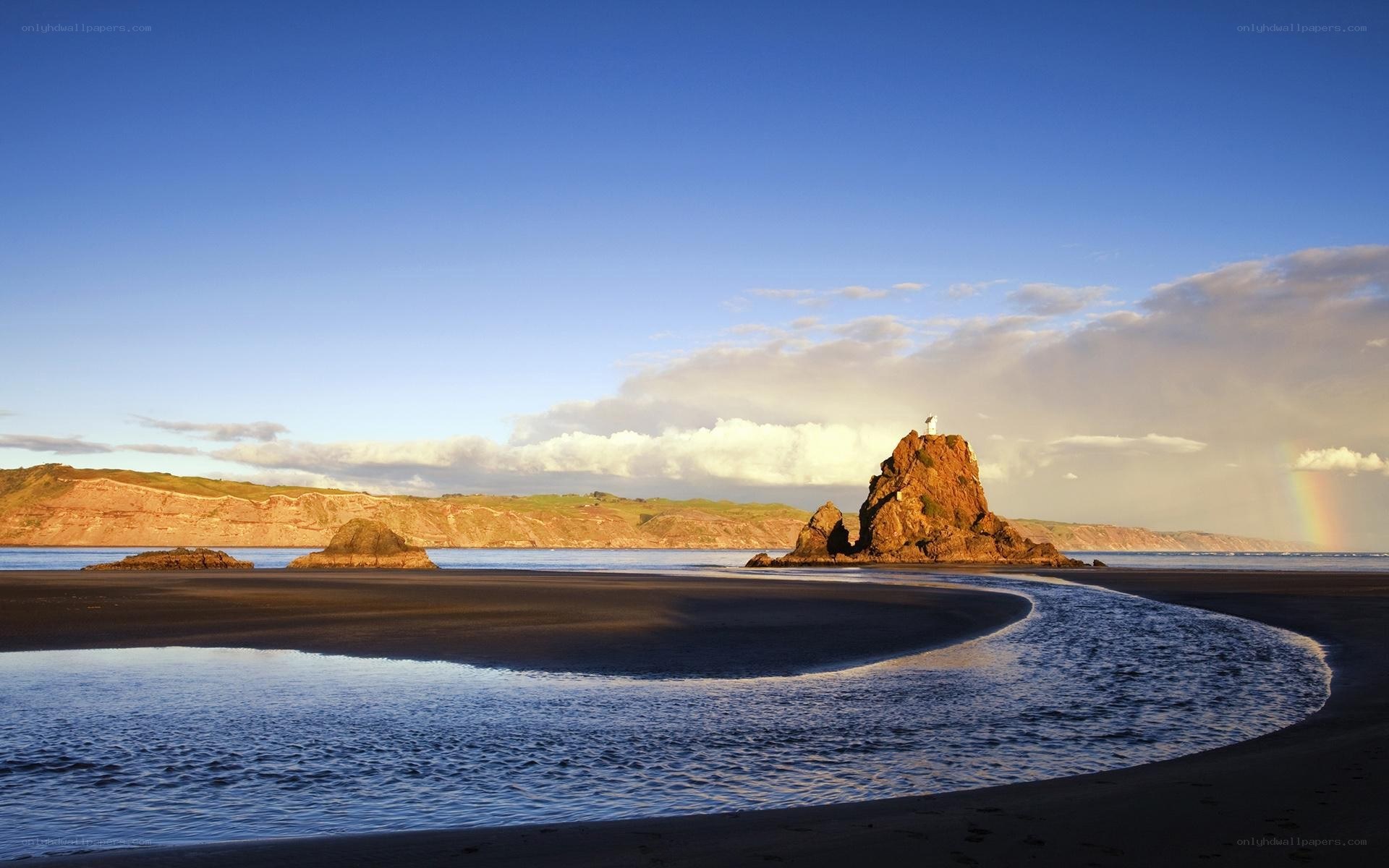 beach with rock formation and rainbow