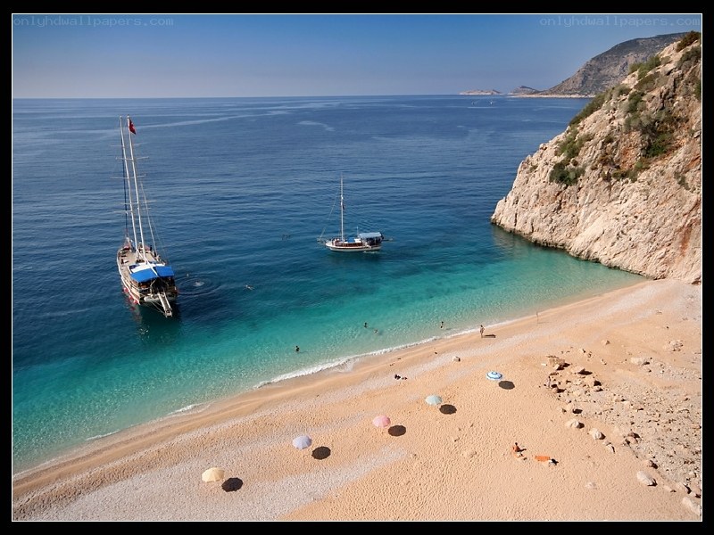 Beach with sailboats and cliffs