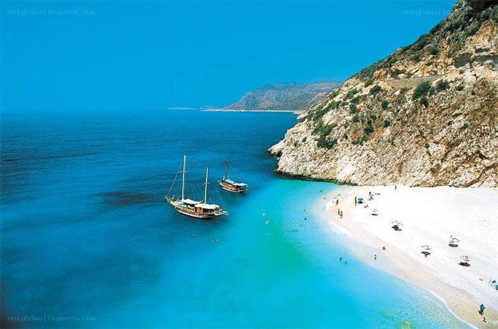 Beach with sailboats and cliffs