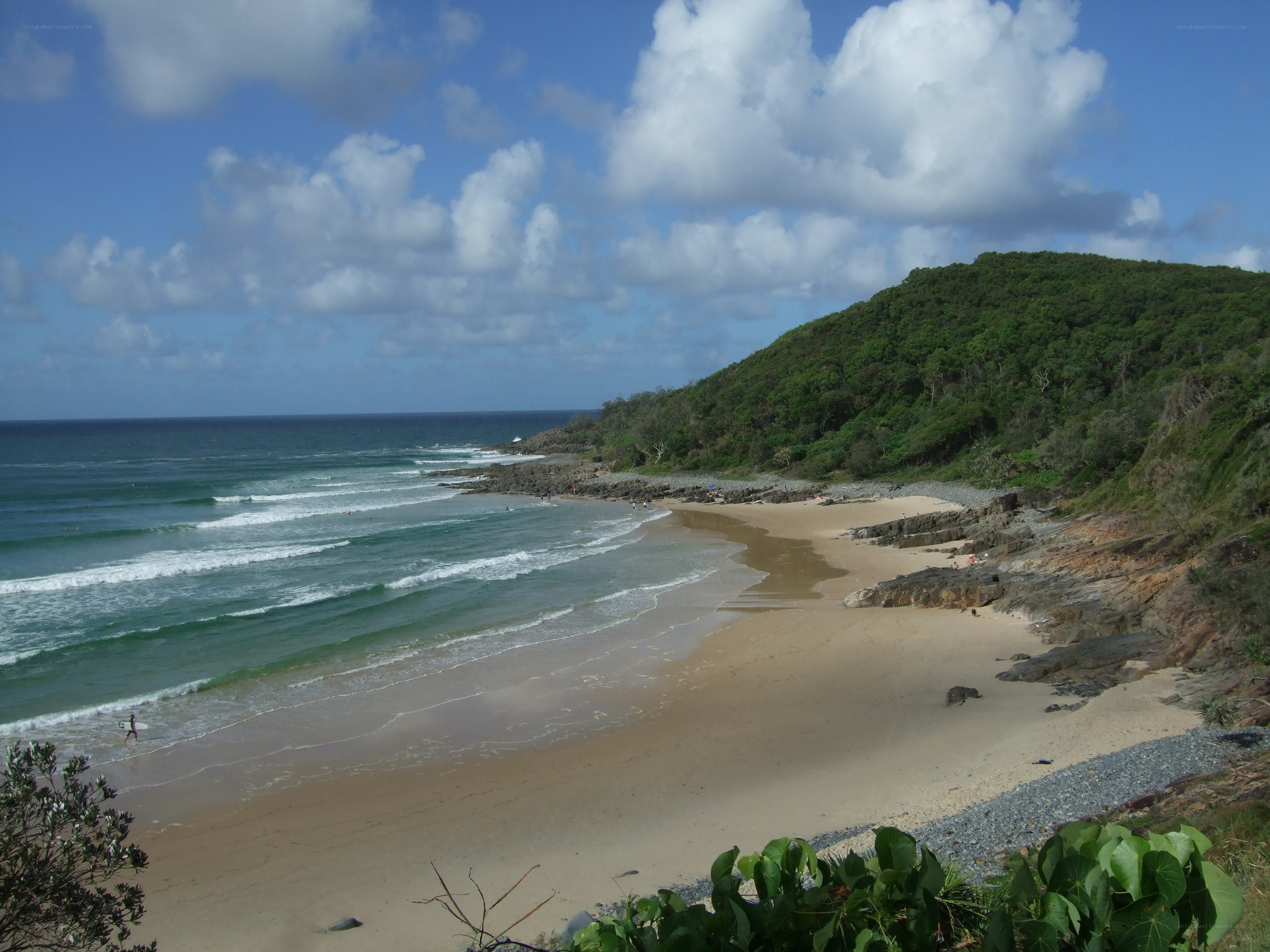beach with waves and green hill