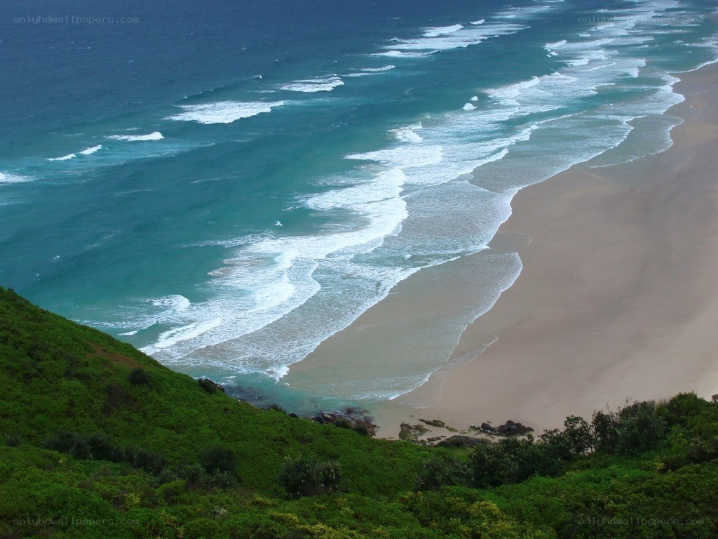 beach with waves and green hill