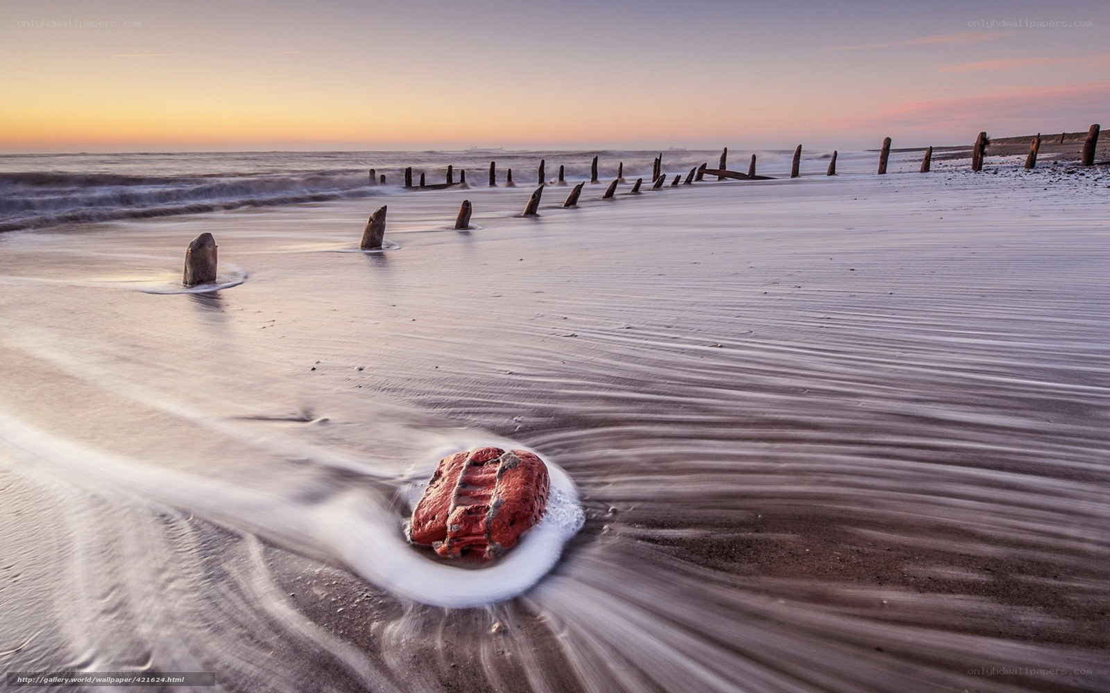 Beach with wooden posts at sunset