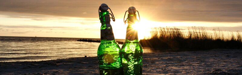 Beer bottles on a beach at sunset