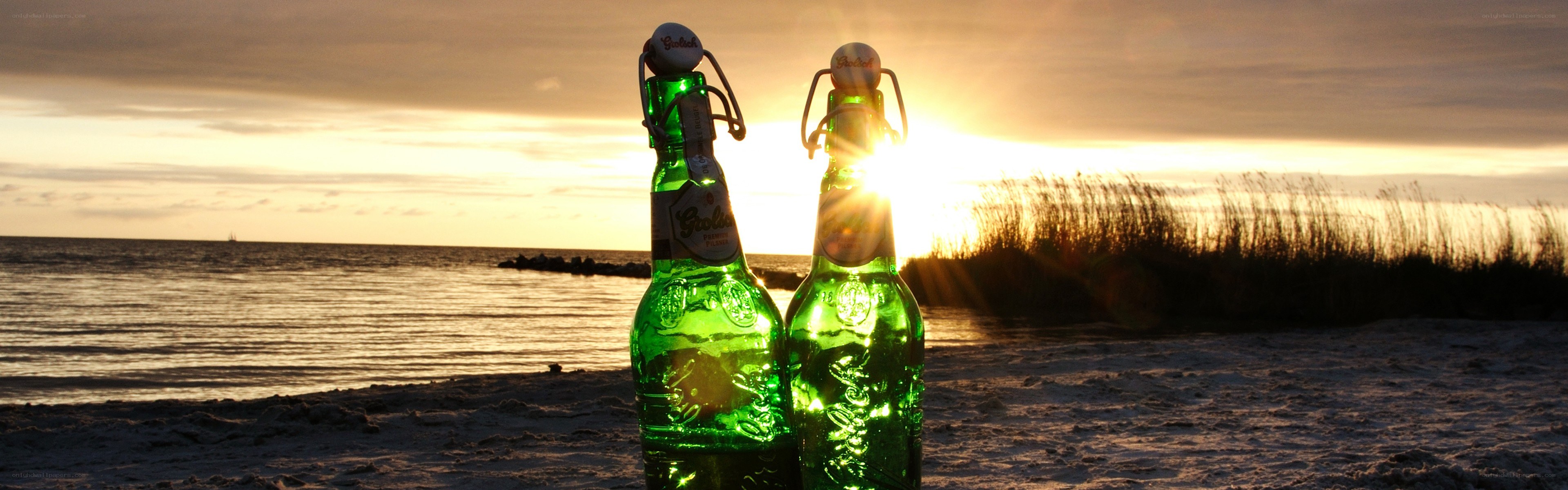 Beer bottles on a beach at sunset