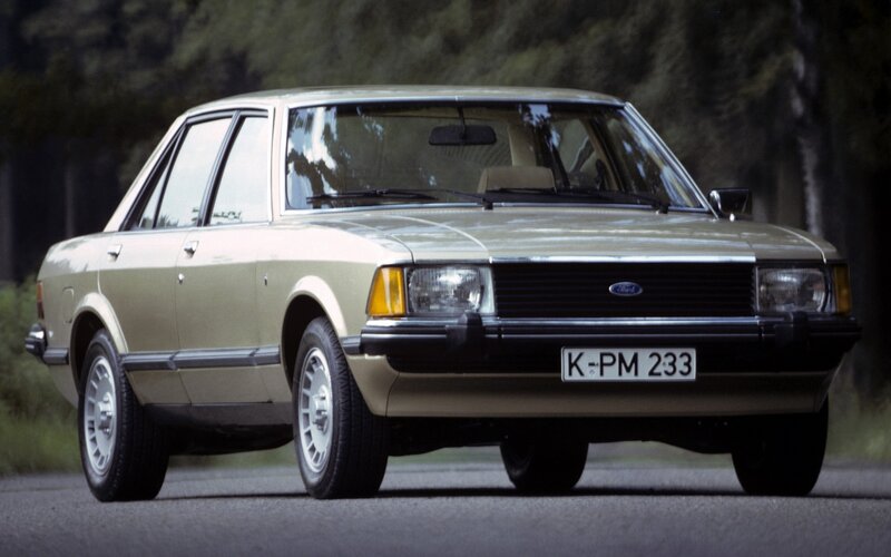 beige ford sedan on road