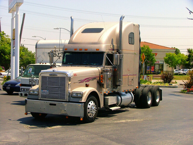 beige semi-truck parked in lot