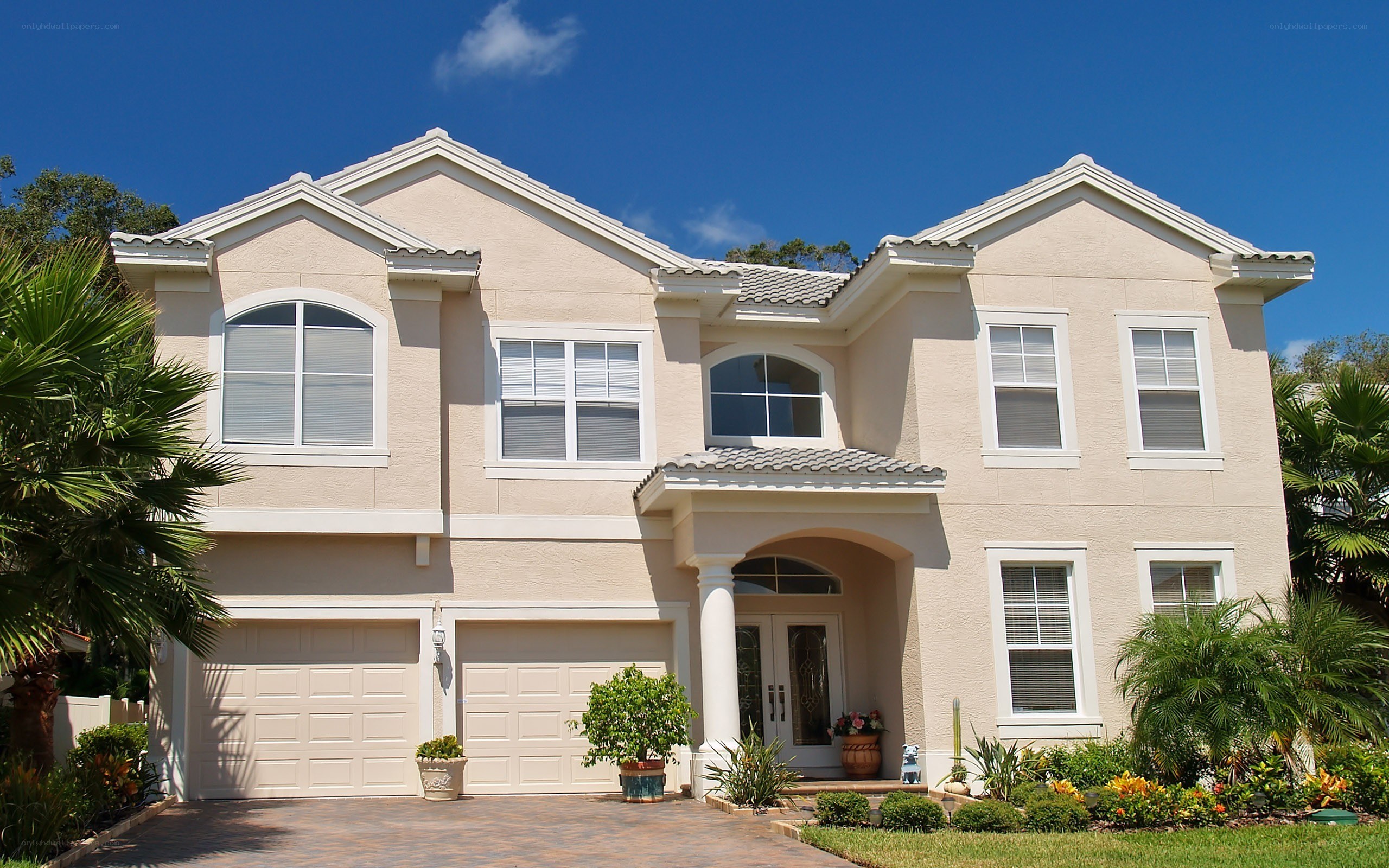 Beige two-story house with palm trees