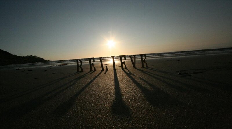 Believe written on beach at sunset