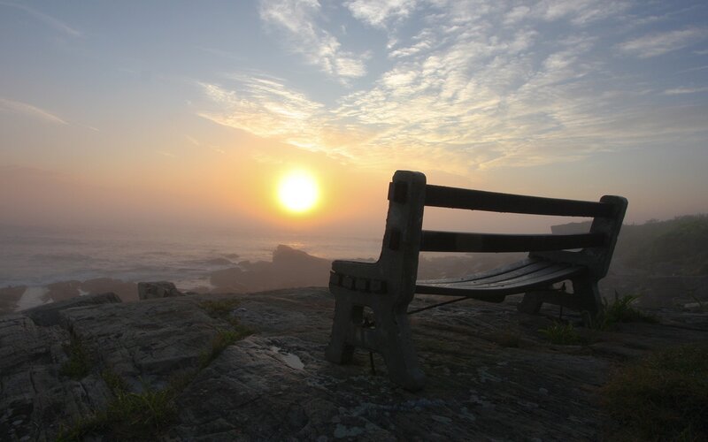 Bench overlooking ocean at sunrise