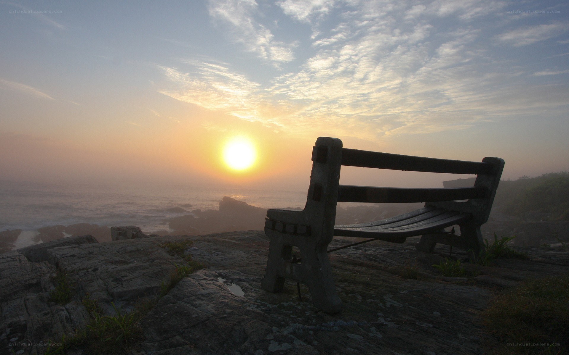 Bench overlooking ocean at sunrise