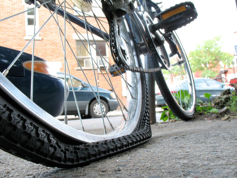 Bicycle with flat tire on sidewalk