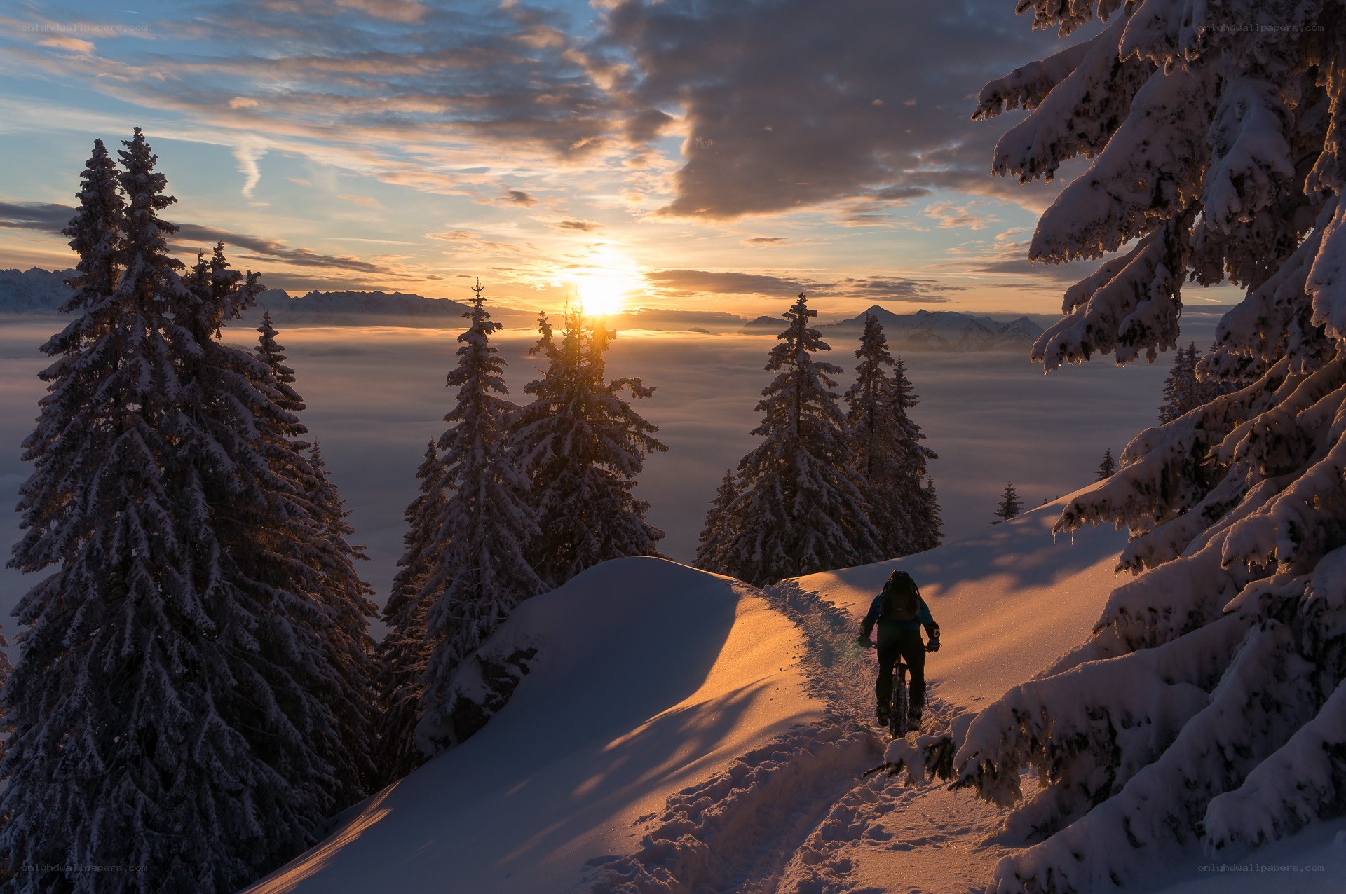 Biker on snowy mountain at sunset