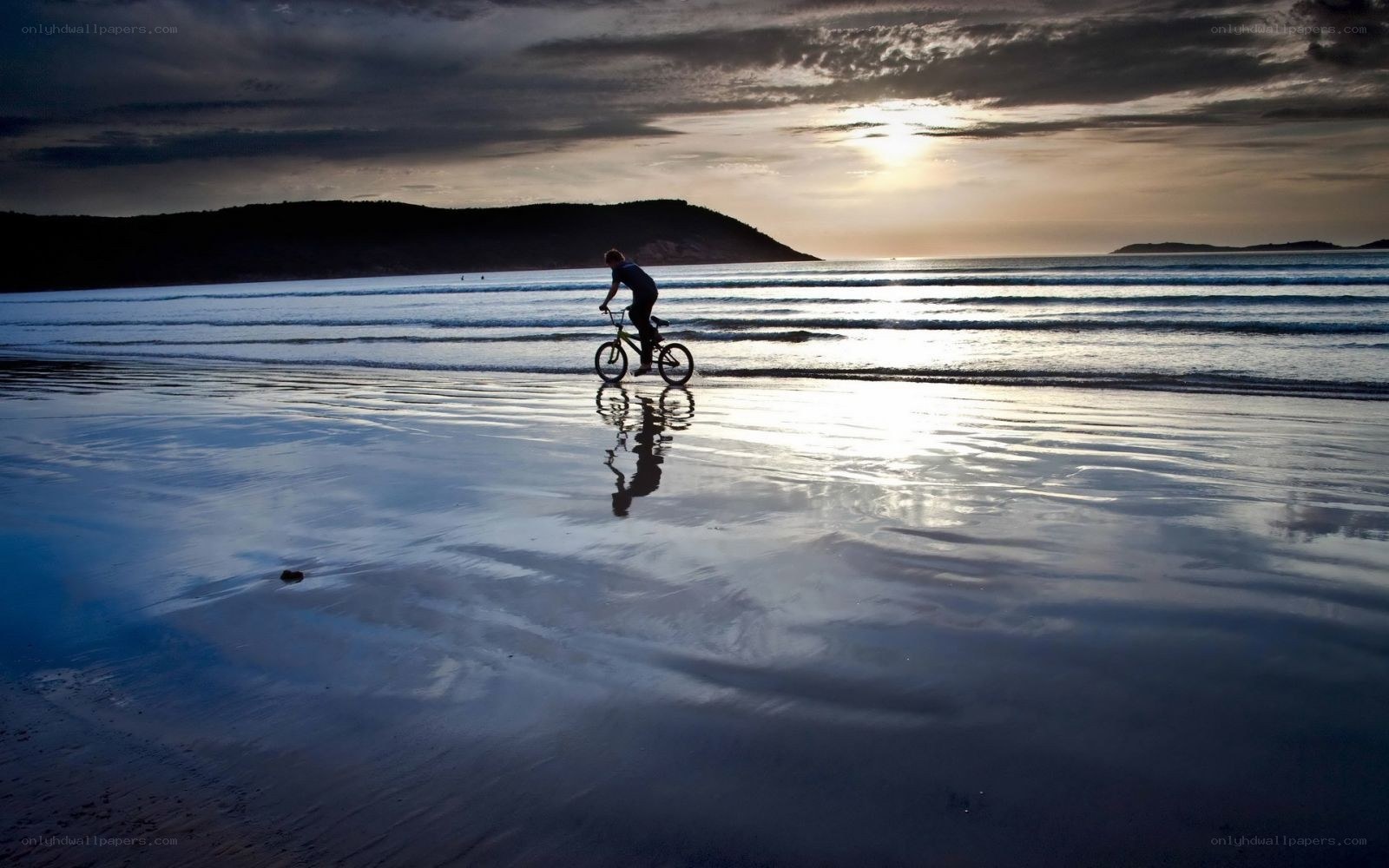 Biker on the beach at sunset