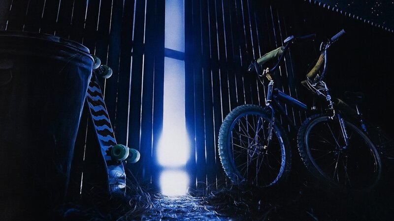 Bikes and skateboard in dark alley