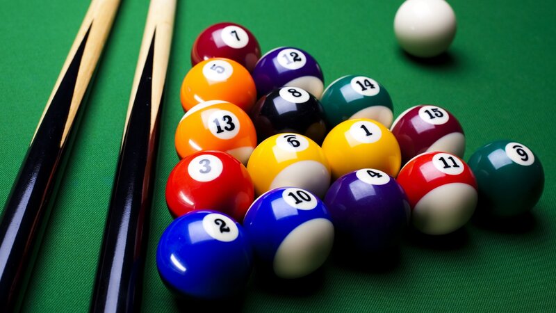 Billiards balls and cues on green table