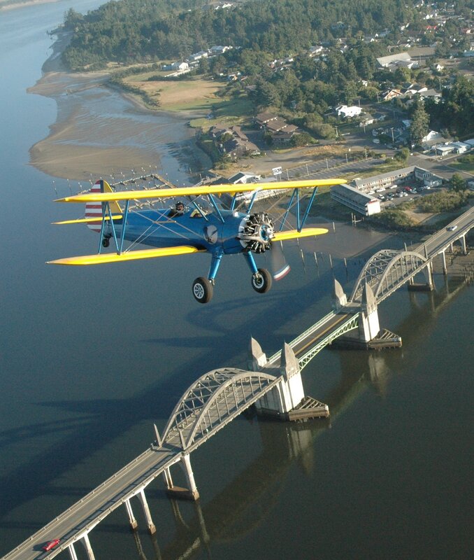 Biplane flying over a bridge
