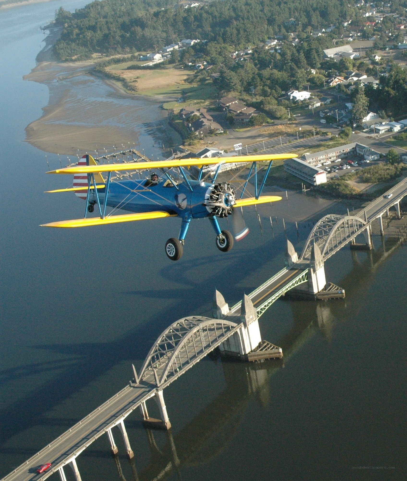 Biplane flying over a bridge
