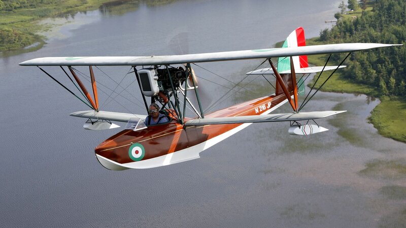 biplane flying over a lake