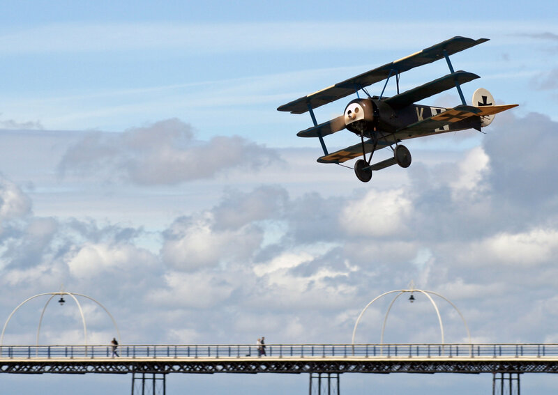 biplane flying over a pier