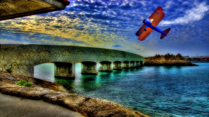 Biplane Flying over Bridge