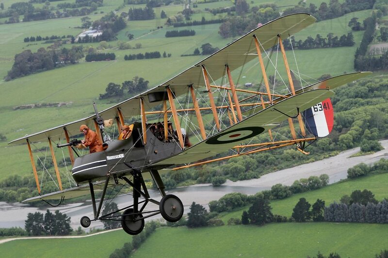 Biplane flying over green fields
