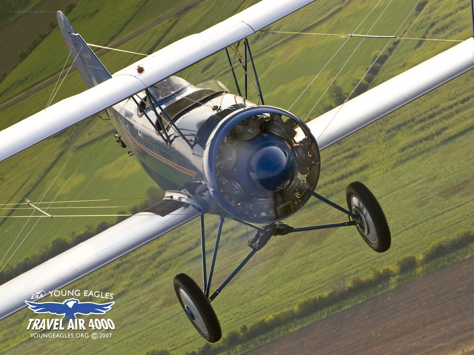 Biplane flying over green fields