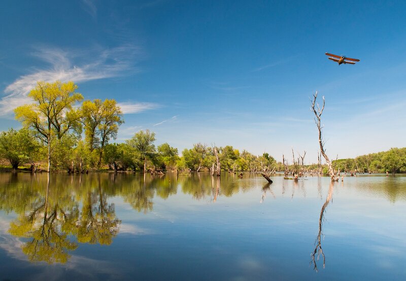 Biplane Flying over River — Blue