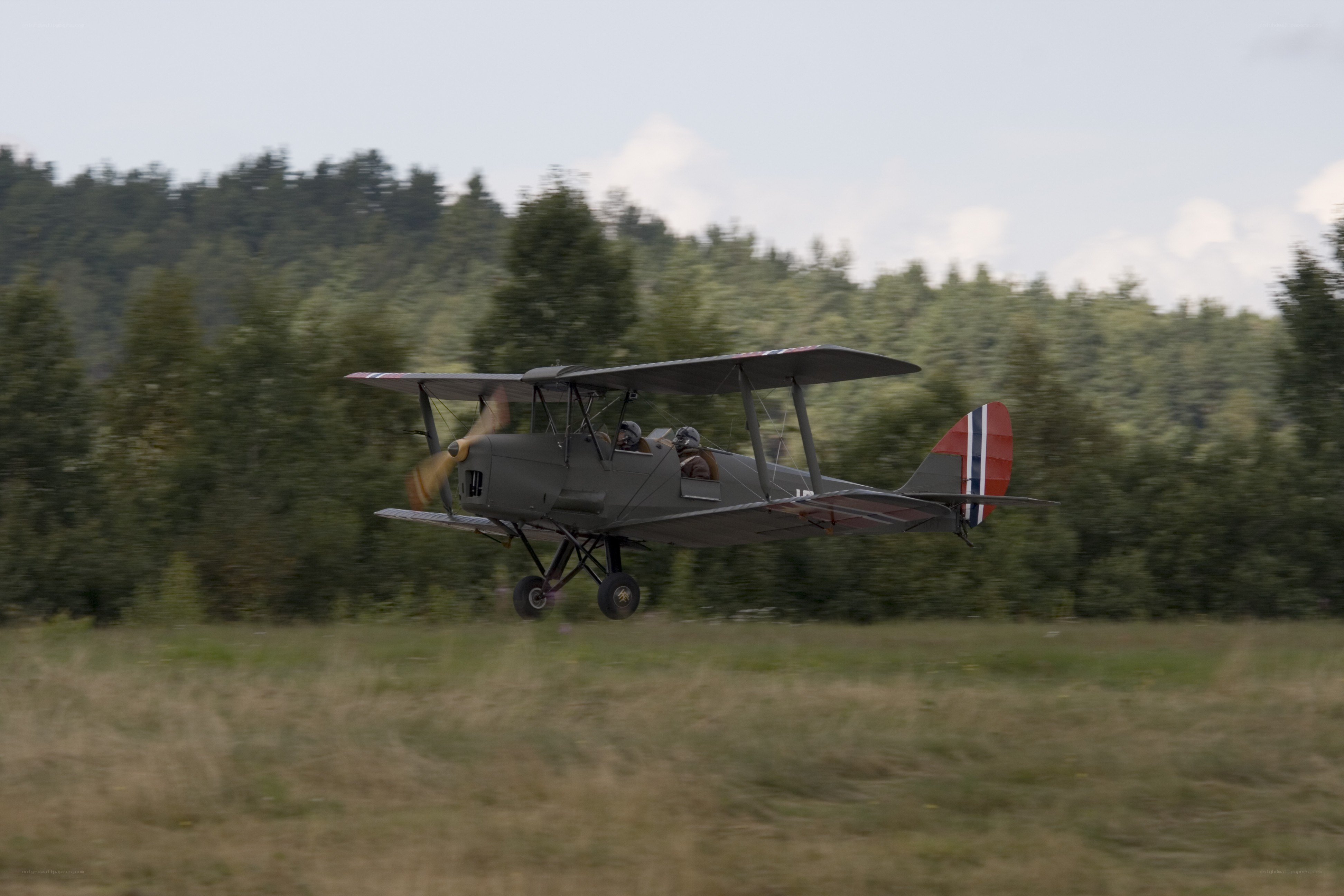 Biplane in flight over field