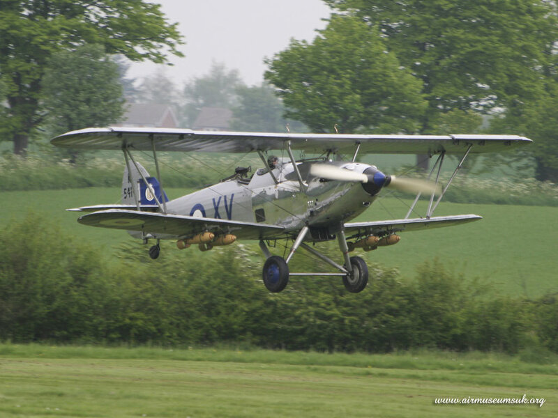 biplane in flight over green field