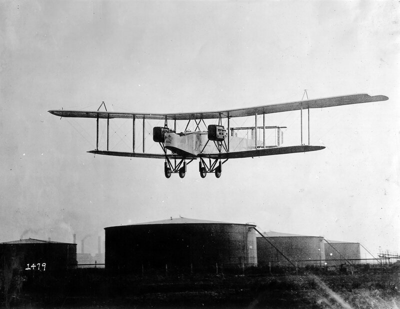 Biplane in flight over tanks