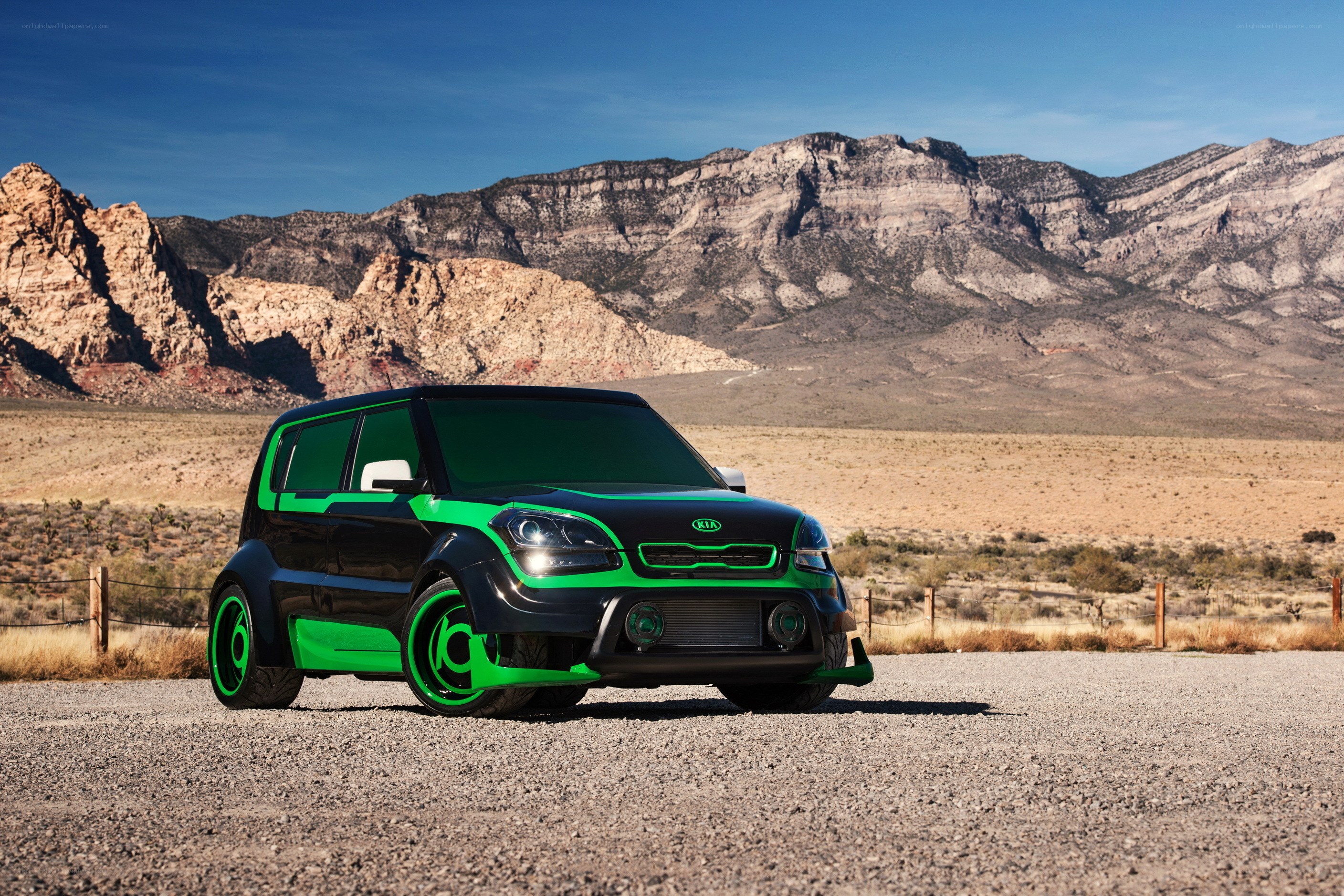 Black and green Kia Soul in desert