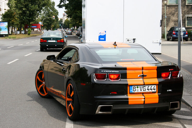 Black and orange Camaro on city street
