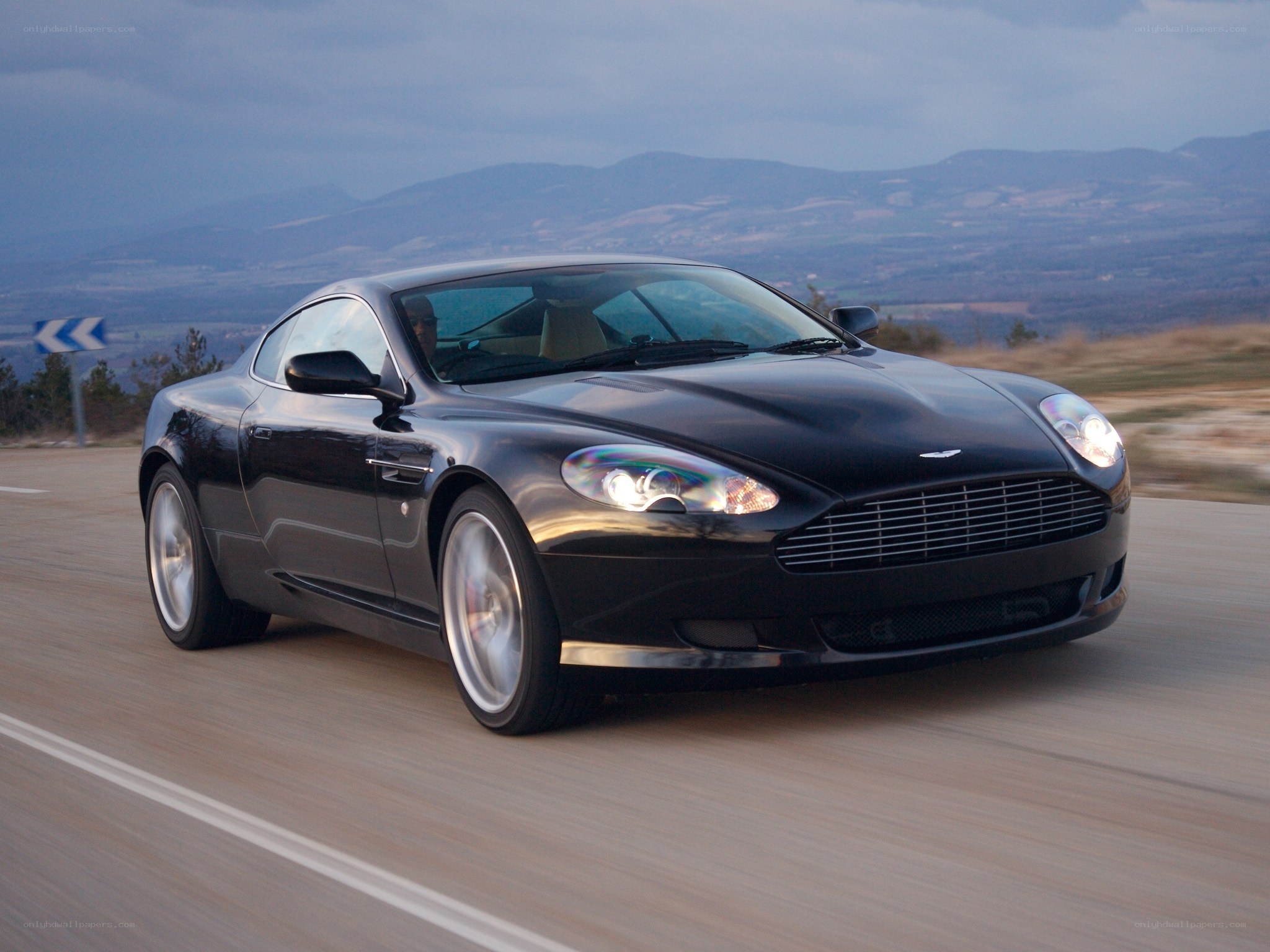 Black Aston Martin on a mountain road