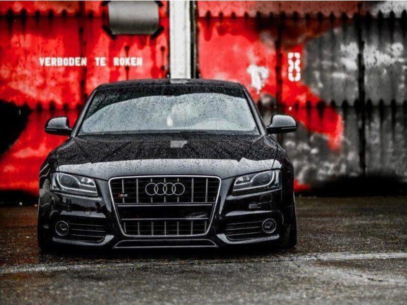 black audi in front of red wall