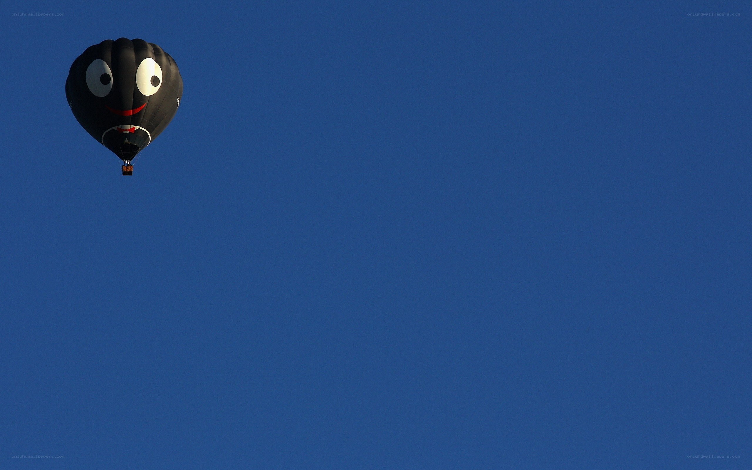 Black balloon with face in blue sky