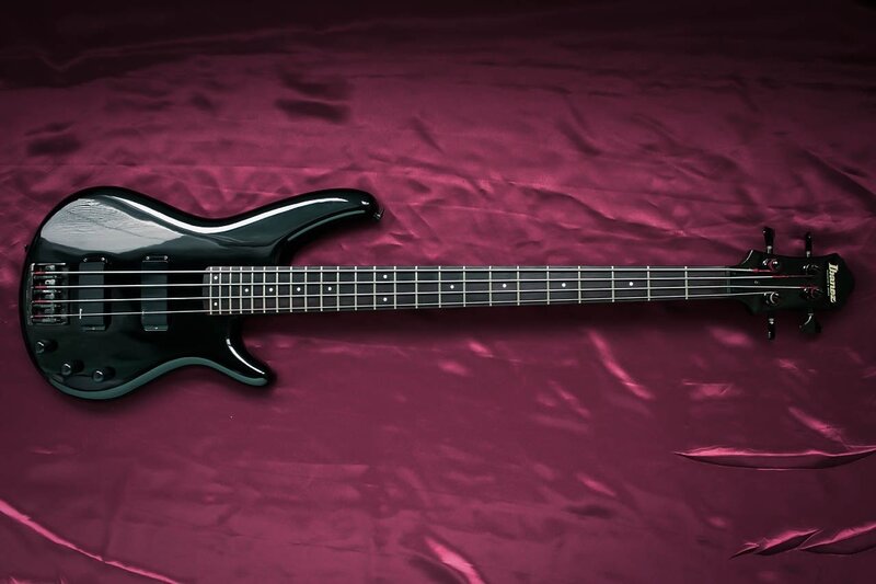 black bass guitar on purple fabric