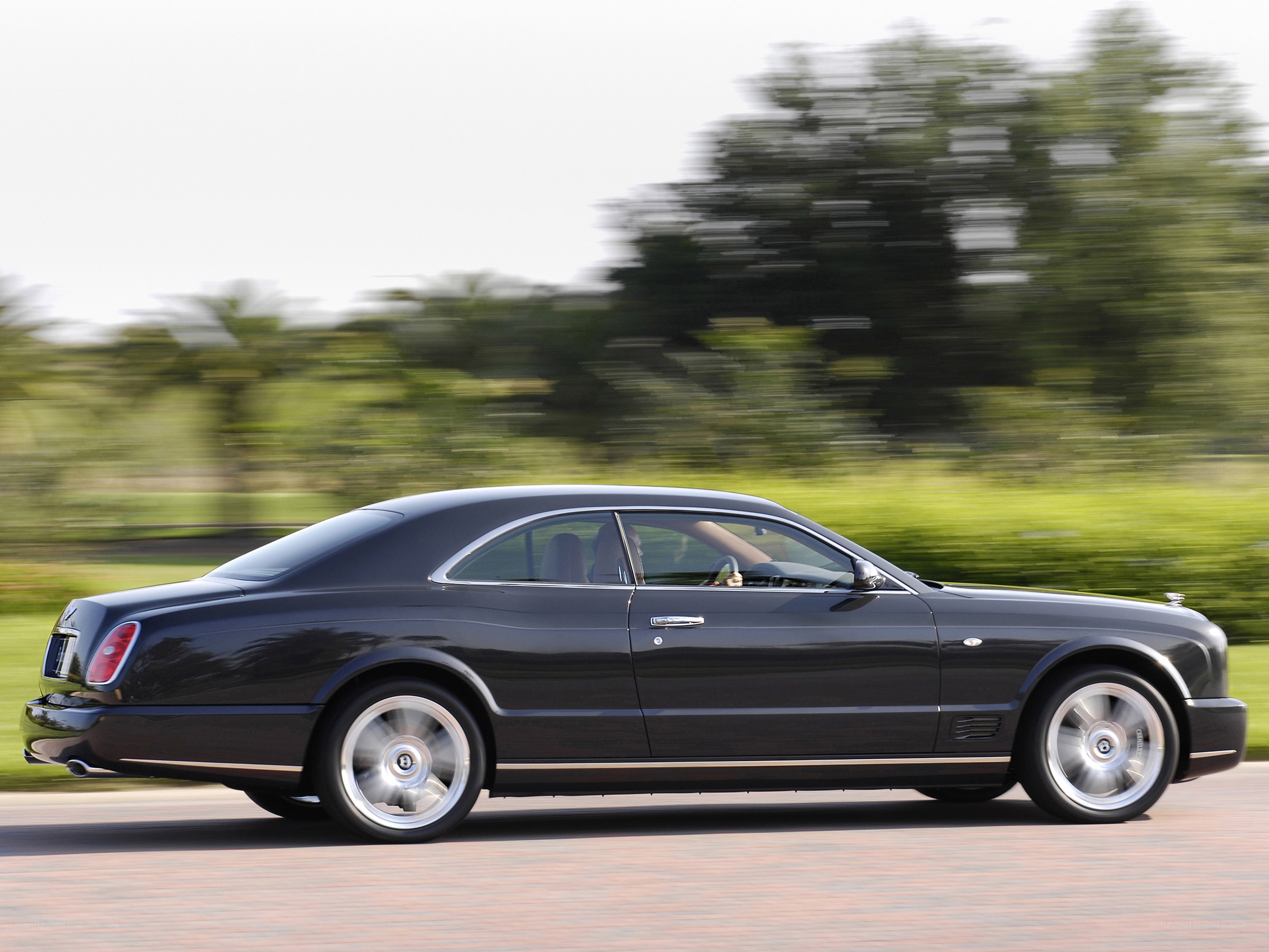 Black Bentley driving on road