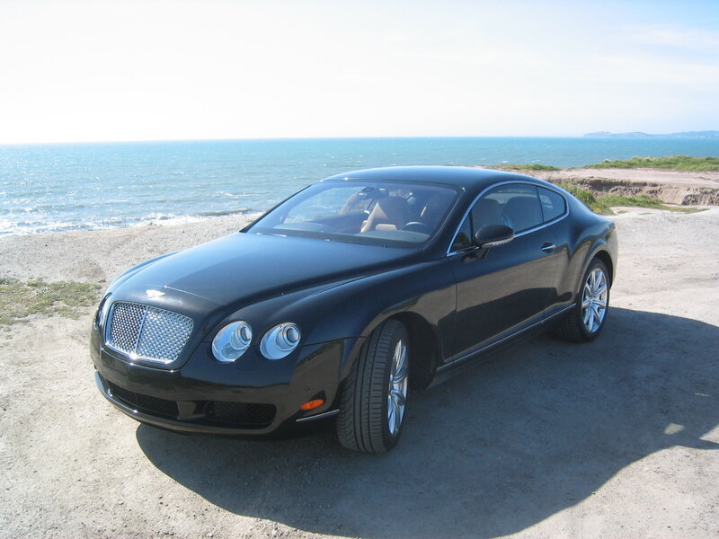 Black Bentley parked by the sea