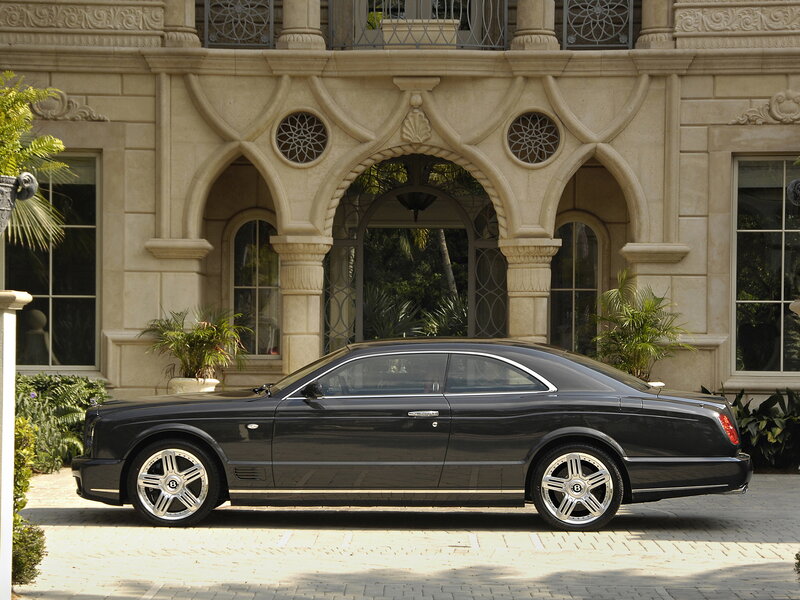 Black Bentley parked in front of mansion