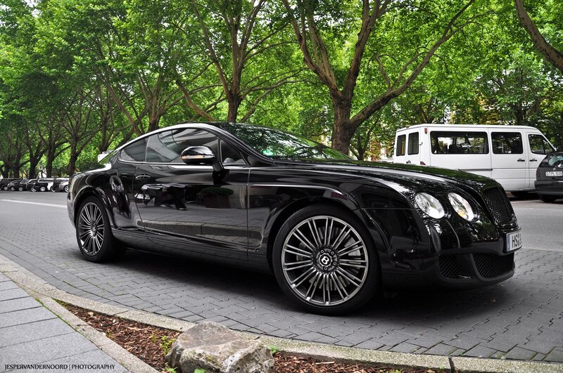Black Bentley parked on a tree-lined street
