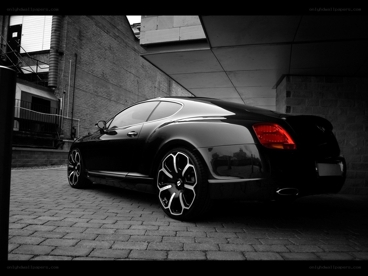 Black Bentley parked on cobblestones