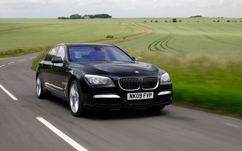 Black BMW driving on country road
