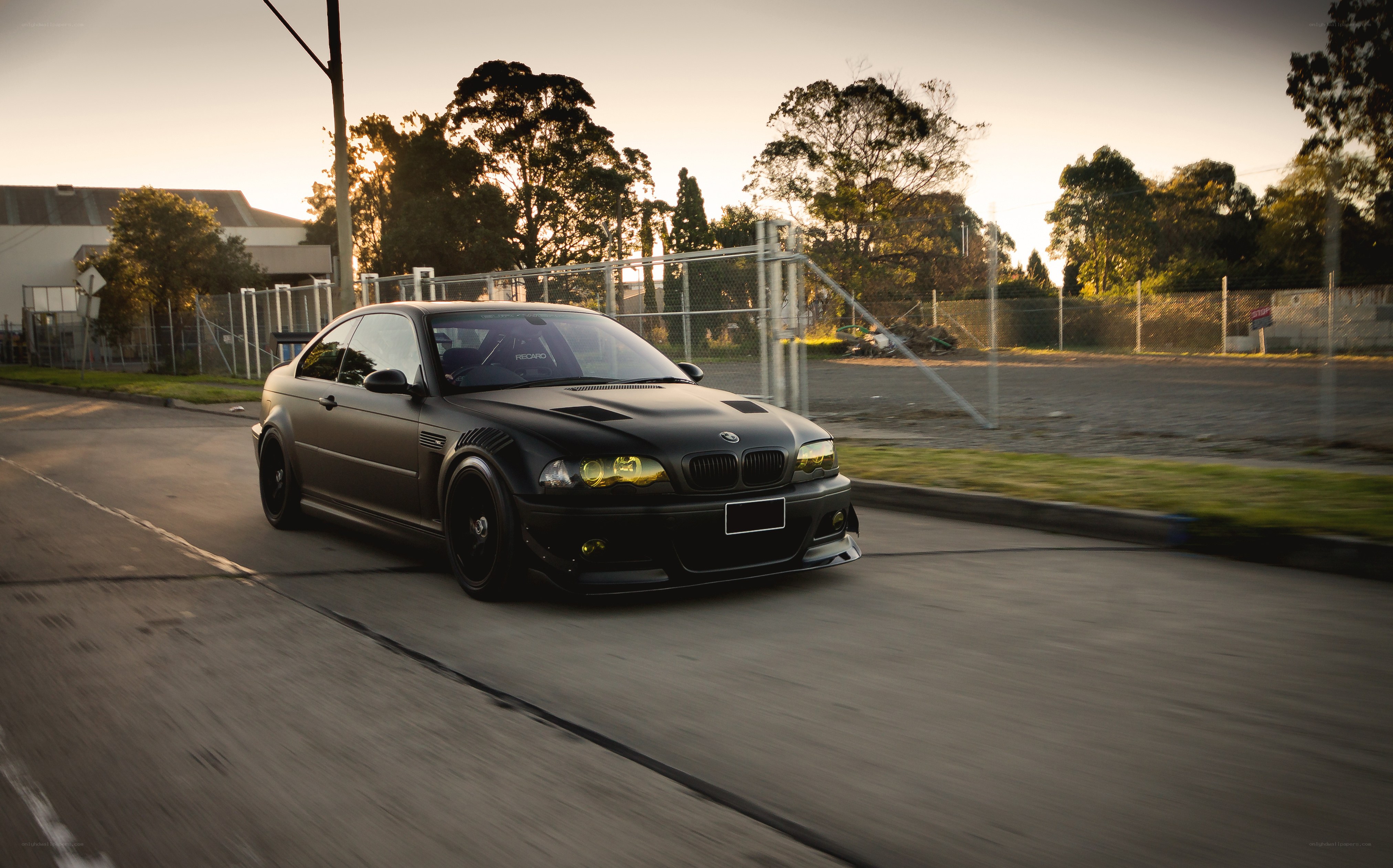 black bmw m3 driving at sunset
