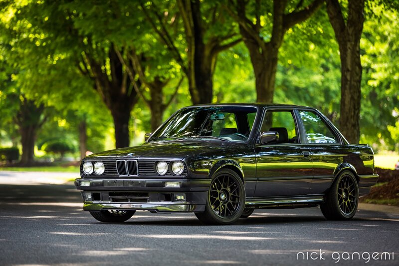 Black BMW parked on a tree-lined street
