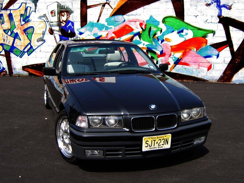 Black BMW sedan in front of graffiti