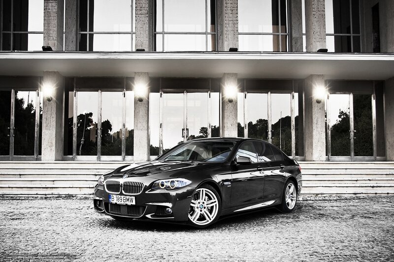 Black BMW sedan in front of modern building