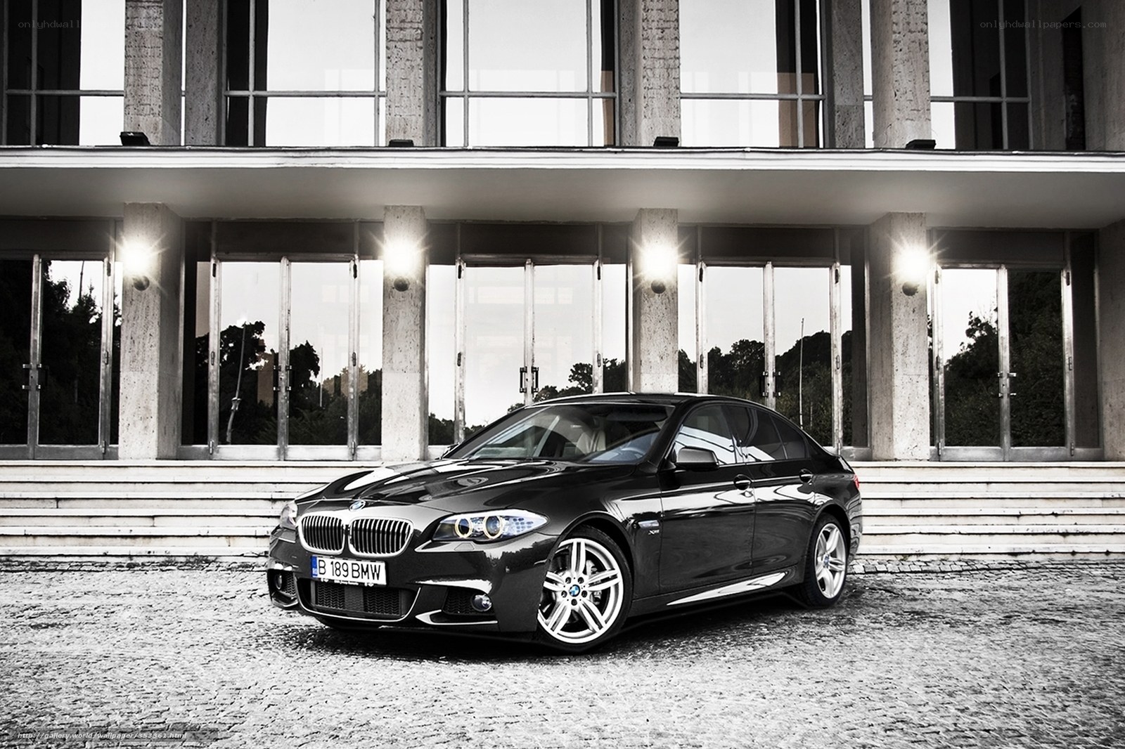Black BMW sedan in front of modern building