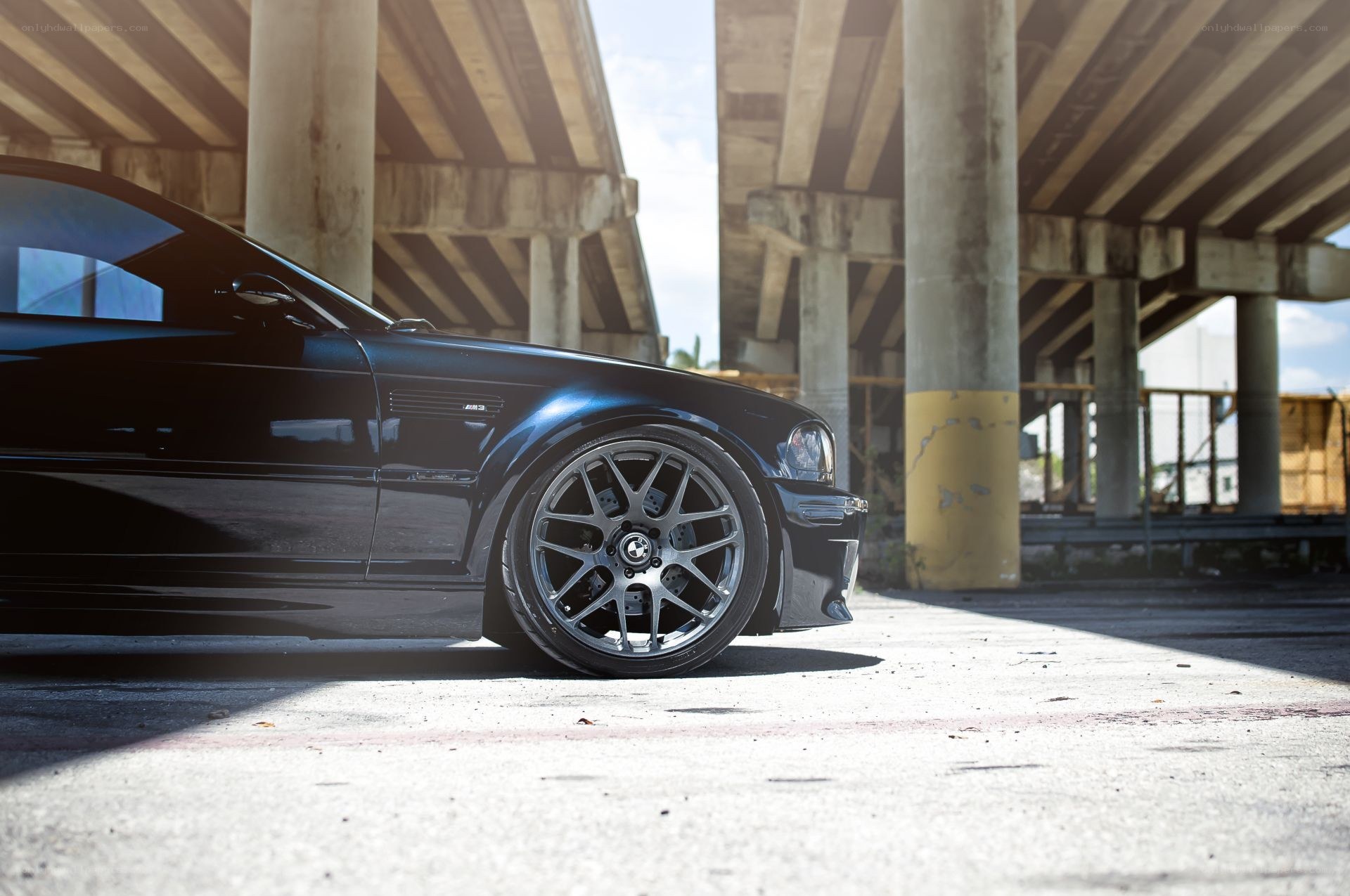 Black BMW under highway overpass