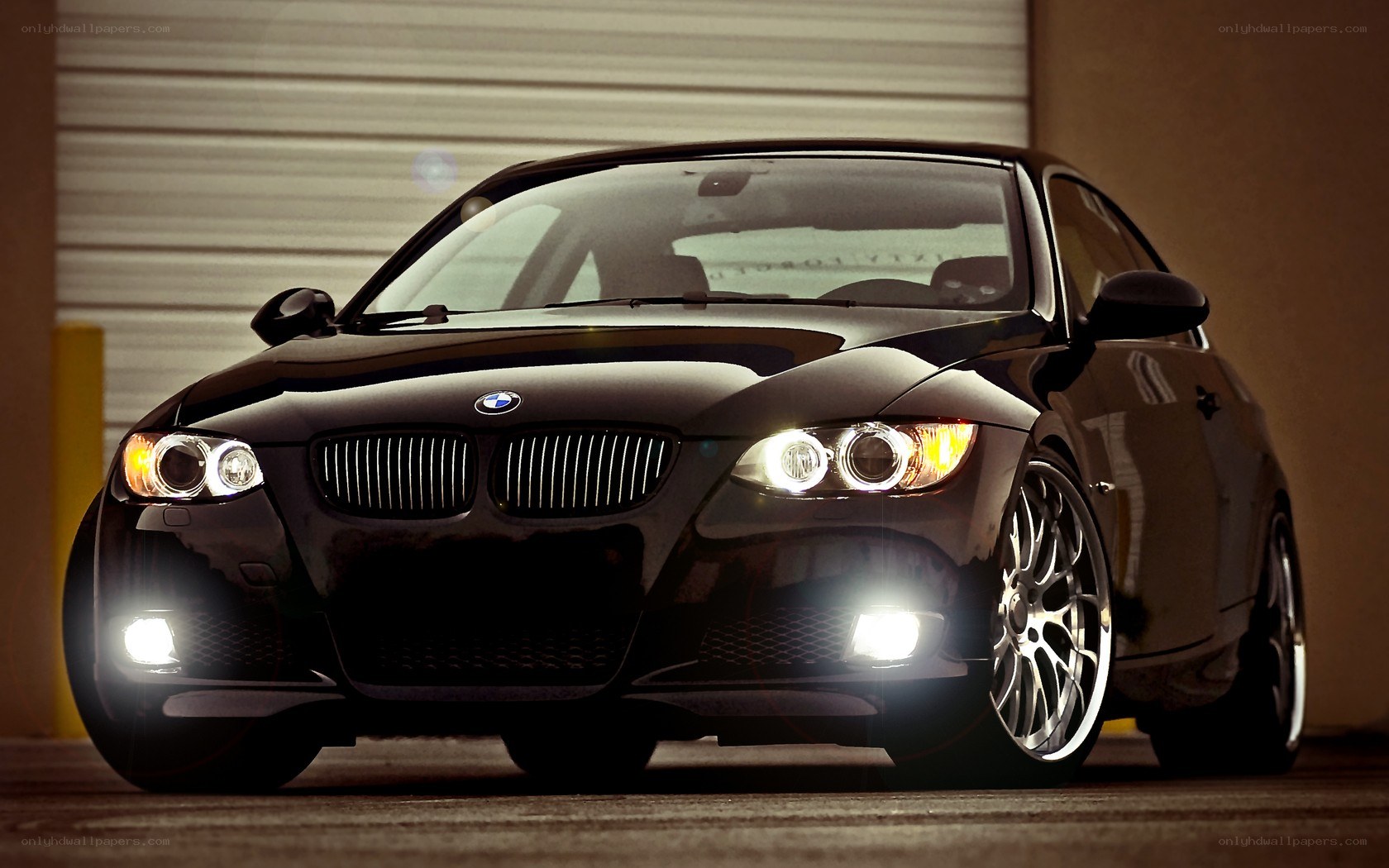 Black BMW with headlights on